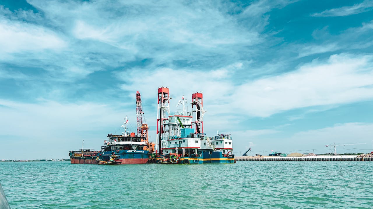 Colorful industrial ships at harbor, vibrant cranes under a bright sky.